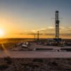 Panorámica de una planta de procesamiento de gas en Vaca Muerta (Argentina), una zona árida con vegetación baja al atardecer.