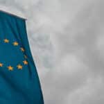 Mundo del mañana. Foto de una bandera de la Unión Europea en formato vertical en un mastil con el cielo nublado y gris