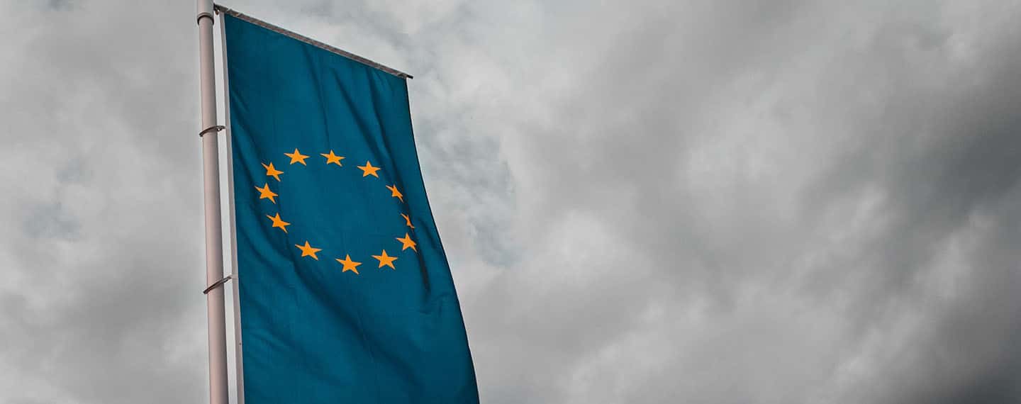 Mundo del mañana. Foto de una bandera de la Unión Europea en formato vertical en un mastil con el cielo nublado y gris