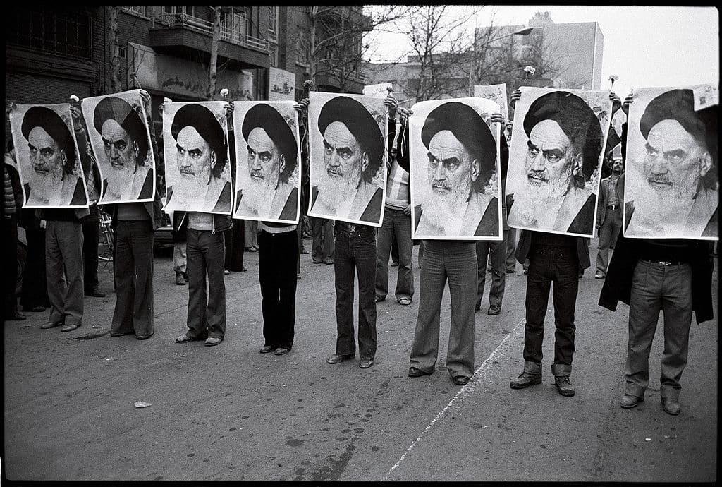 Una fila de hombres sostienen la imágen del ayatolá Jomeini durante una manifestación en Irán (1978). Fotografía escaneada, autor desconocido (Wikimedia Commons / Dominio público). Blog Elcano