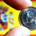 A euro coin with the Spanish national flag in the background. Elcano Blog