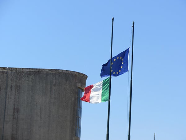 Salvini’s Italy between Greek tragedy and Portuguese fado. Flags of Italy and the European Union.