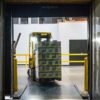 Problemas en las cadenas de suministro. Un operario conduce una carretilla elevadora amarilla y negra en un almacén