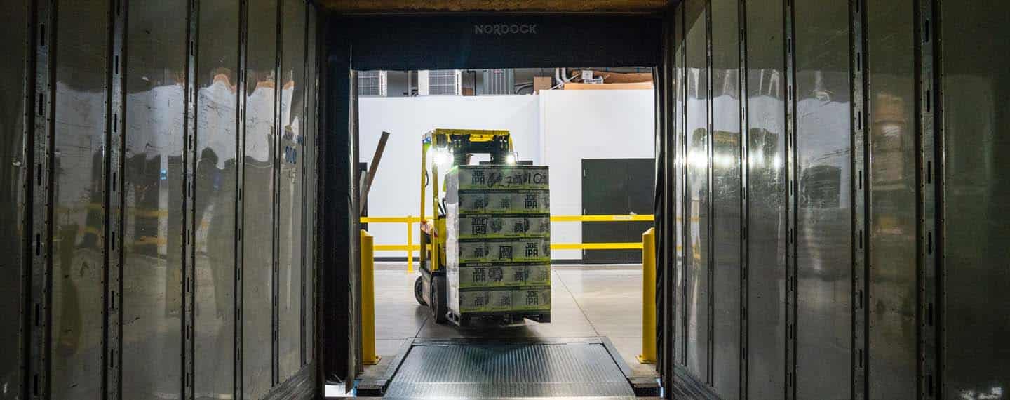 Problemas en las cadenas de suministro. Un operario conduce una carretilla elevadora amarilla y negra en un almacén