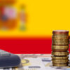 Ups and downs of the Spanish economy. Calculator with money and coins in front of flag of Spain