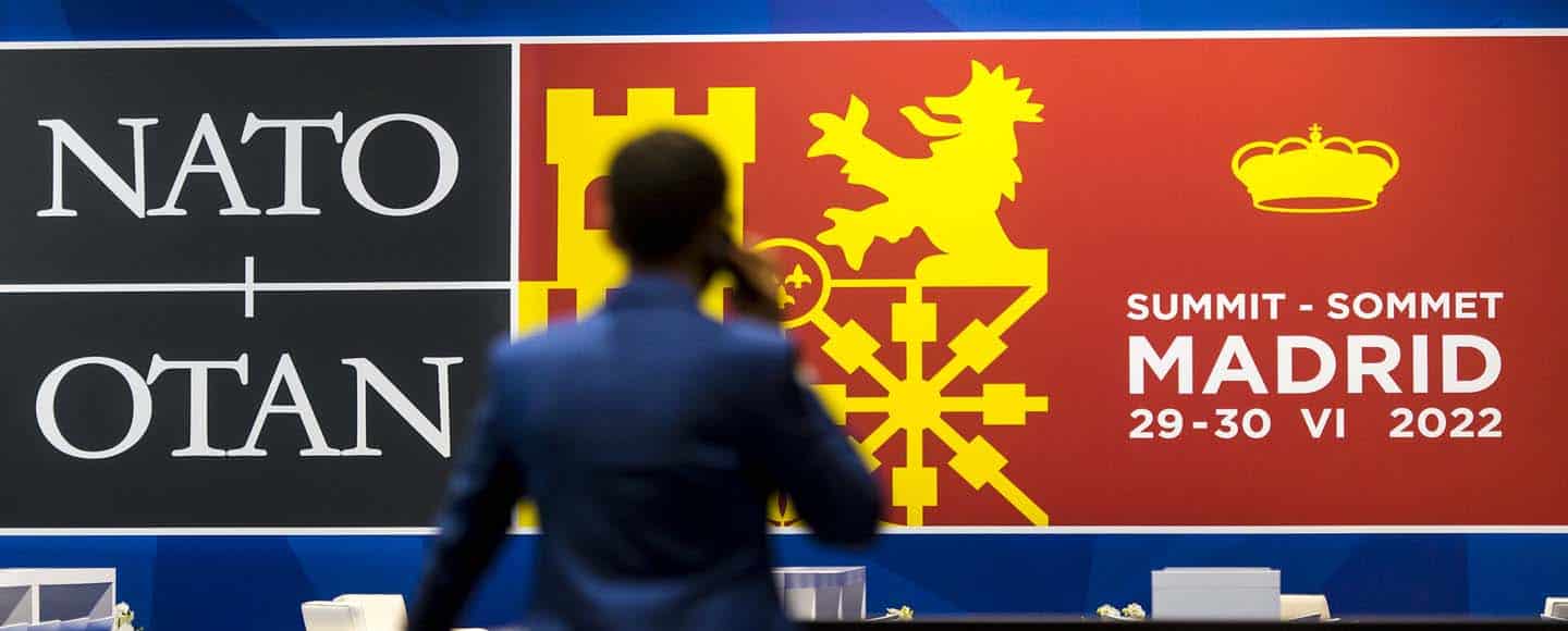 Antiterrorismo. Un hombre de espaldas habla por teléfono ante el cartel de la Cumbre de la OTAN en Madrid, 2022