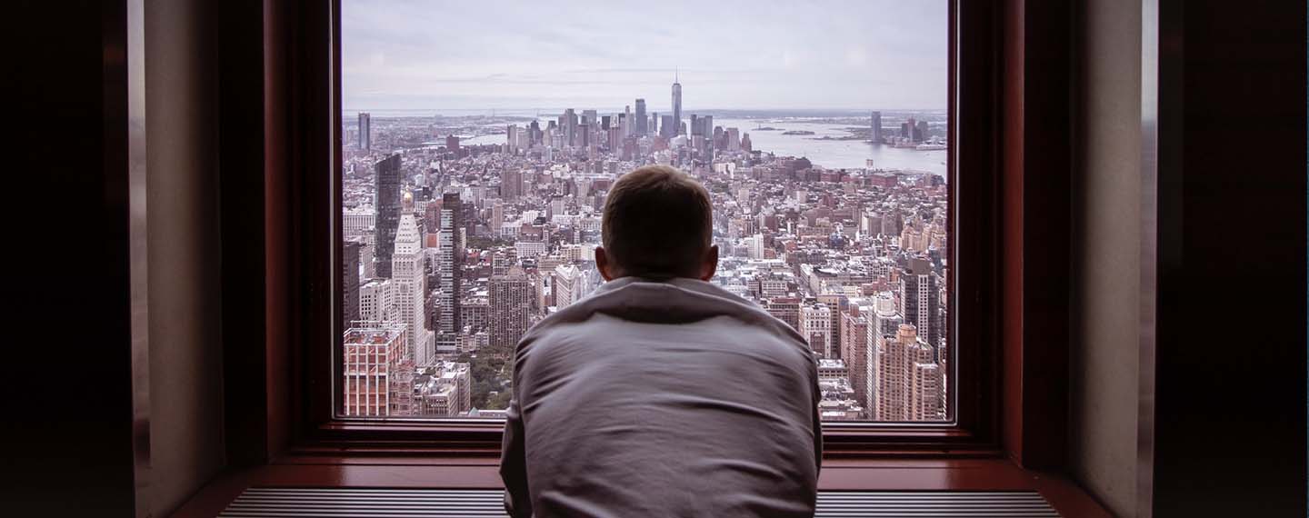 La intimidad de la mente. Hombre con camisa gris mirando los edificios de una ciudad durante el día