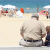 Children. An old man sitting besides a girl on a bench in a beach