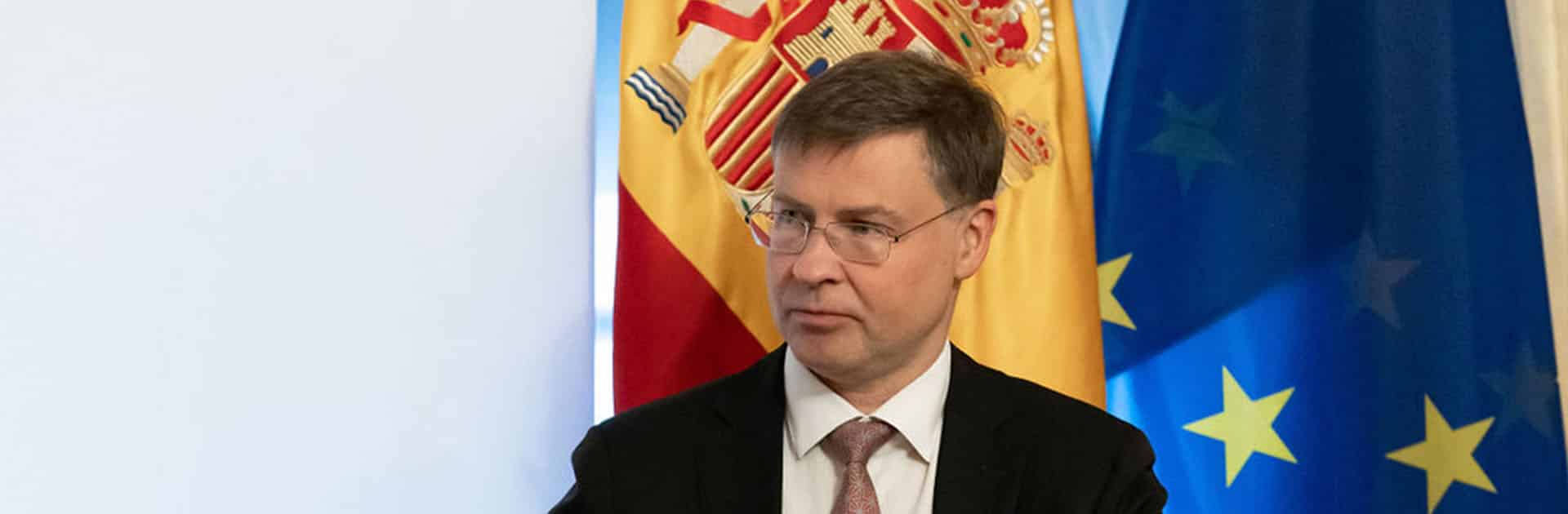 Foreground: Valdis Dombrovski, European Commission Executive Vice-President for an Economy that Works for People and Commissioner for Trade. Background: flags of Spain and the European Union