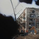 Workers and a bulldozer work around a building destroyed by the bombing of Kyiv in March 2022. War in Ukraine