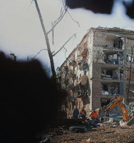 Obreros y una máquina excavadora trabajan en los alrededores de un edificio destruido por los bombardeos en Kyiv en marzo de 2022. Guerra en Ucrania