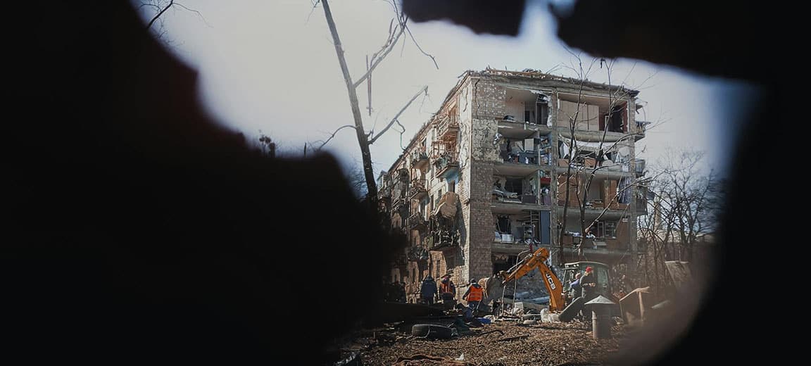 Obreros y una máquina excavadora trabajan en los alrededores de un edificio destruido por los bombardeos en Kyiv en marzo de 2022. Guerra en Ucrania