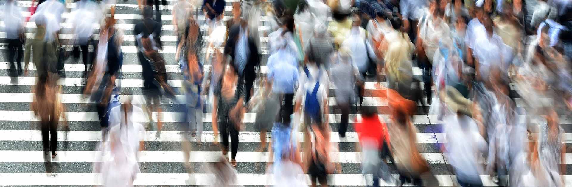 Barómetro del Real Instituto Elcano. Imagen desenfocada de una multitud de personas cruzando por un paso de cebra en una calle