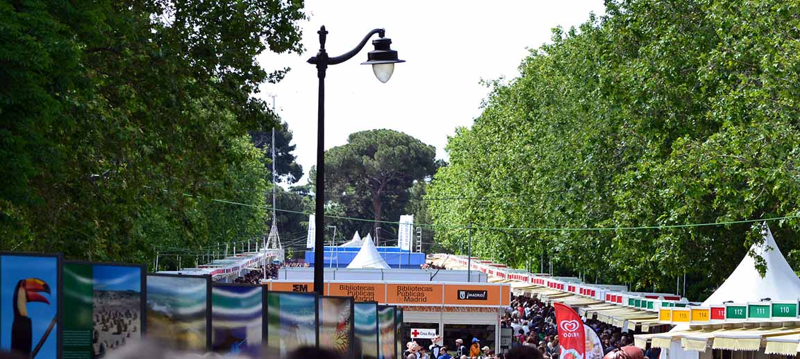 Imagen de la Feria del Libro de Madrid de 2013 en el Parque del Retiro con un multitud de personas, las casetas y los pabellones centrales