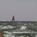 North Africa. Three young men running on a surface of water with rocks.