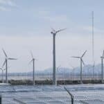 Transición energética. Turbinas eólicas y paneles solares durante el día. La energía solar fotovoltaica y la eólica terrestre son las formas más baratas de generar electricidad.