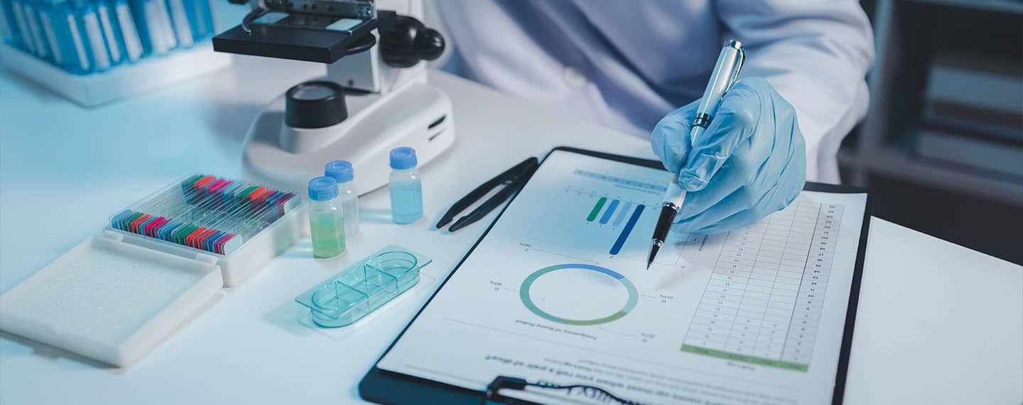 Una persona trabajando con un microscopio y muestras en un laboratorio, realizando trabajos de investigación científica