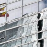 Spanish flag reflected in the windows of a building in the Cuatro Torres Business Area in Madrid (Spain)