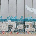A wall at Netiv HaAsara facing the Gaza border reads the words “Path to Peace” in Hebrew, Arabic, and English. Netiv HaAsara is a moshav in southern Israel. Located in the north-west Negev, it nearly borders the Gaza Strip