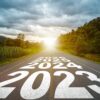 Texto año 2023, 2024, 2025 escrito en medio de una carretera de asfalto con el atardecer al fondo, en un paisaje rural y boscoso. Concepto de planificación, meta, desafío, resolución de año nuevo