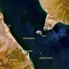 Fotografía aérea del estrecho Bab-el-Mandeb que enlaza el Mar Rojo con el Golfo de Adén, con las descripciones países costeros (a la izquierda, Yibuti, y a la derecha, Yemen), Ras Siyan en la costa africana, la isla de Perim, y las islas de Sawabi