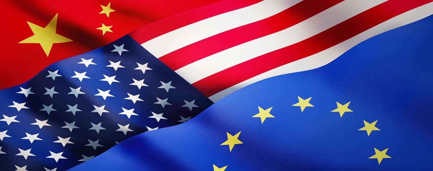 Banderas china, estadounidense y europea ondeando a la luz del sol como fondo. China, EEUU y la UE conforman un triángulo estratégico