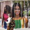 Una mujer de mediana edad con una mochila pasa frente a un panel de fotografías de la conferencia internacional sobre política exterior feminista Shaping Feminist Foreign Policy (SFFP), realizada en el Foro Mundial de La Haya en noviembre de 2023