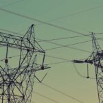 Torres de transmisión de energía eléctrica sobre el fondo de un cielo con tonos verdoso. Mercado eléctrico