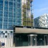 Headquarters of the International Criminal Court (ICC) in The Hague. In the left foreground, a blue sign with the ICC logo. In the background, a bicycle parking area and the visitors’ entrance to the building