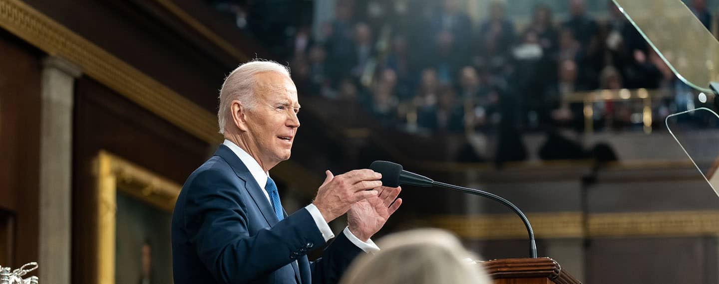 El presidente Joe Biden de pie ante el podio con un micrófono pronuncia su discurso sobre el Estado de la Unión, el martes 7 de febrero de 2023, en el hemiciclo del Capitolio de Estados Unidos en Washington, D.C. Fotografía oficial de la Casa Blanca por Adam Schultz