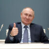 Vladimir Putin, sentado en una mesa con dos micrófonos a los lados y con dos banderas de Rusia al fondo, sonríe levantado el pulgar de su mano derecha durante una video conferencia con Recep Tayyip Erdoğan, presidente de Turquía, con motivo de la ceremonia del inicio de la construcción de la tercera unidad de potencia de la central nuclear de Akkuyu en la provincia turca de Mersin