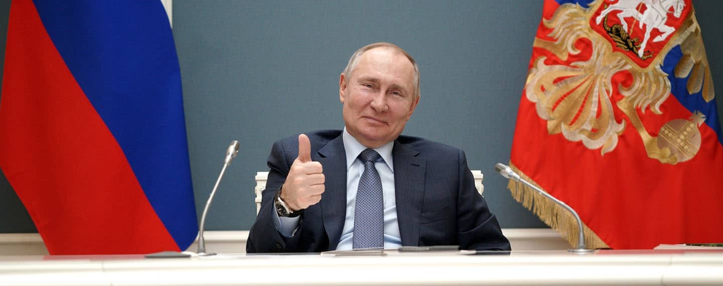Vladimir Putin, sentado en una mesa con dos micrófonos a los lados y con dos banderas de Rusia al fondo, sonríe levantado el pulgar de su mano derecha durante una video conferencia con Recep Tayyip Erdoğan, presidente de Turquía, con motivo de la ceremonia del inicio de la construcción de la tercera unidad de potencia de la central nuclear de Akkuyu en la provincia turca de Mersin
