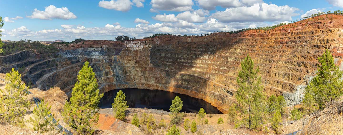 Detalle de un túnel en medio de una montaña en las minas de Riotinto en Huelva. Fondo: Cielo azul con cúmulos de nubes durante el día.