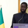 El nuevo presidente de Senegal, Bassirou Diomaye Faye, durante la rueda de prensa con motivo de la visita de Charles Michel, presidente del Consejo Europeo, en Dakar. Fondo: Banderas de Senegal y de la Unión Europea.