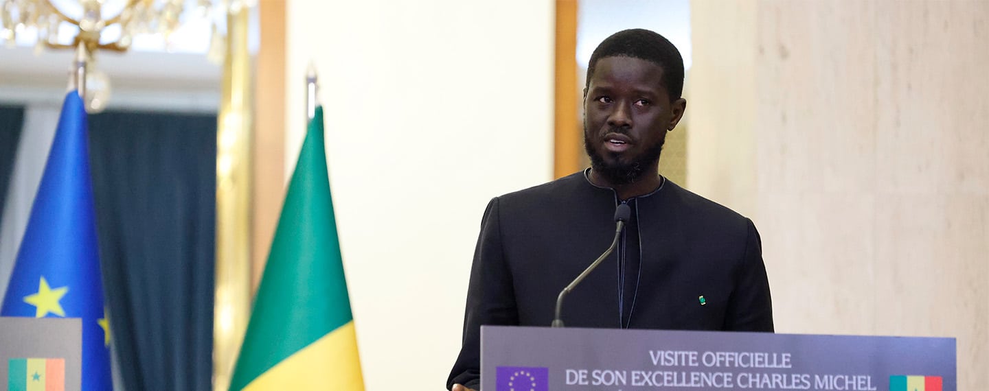El nuevo presidente de Senegal, Bassirou Diomaye Faye, durante la rueda de prensa con motivo de la visita de Charles Michel, presidente del Consejo Europeo, en Dakar. Fondo: Banderas de Senegal y de la Unión Europea.