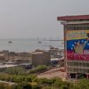 Vista de las Torres de PDVSA desde el campanario de la Basílica de la Virgen de Chiquinquirá, en la ciudad de Maracaibo (Venezuela). En la torre en primer plano cuelga un cartel de propaganda del gobierno, con el lema "¡Chávez vive! ¡La lucha sigue!". Al fondo, el lago de Maracaibo con buques cargueros y el puente sobre el lago
