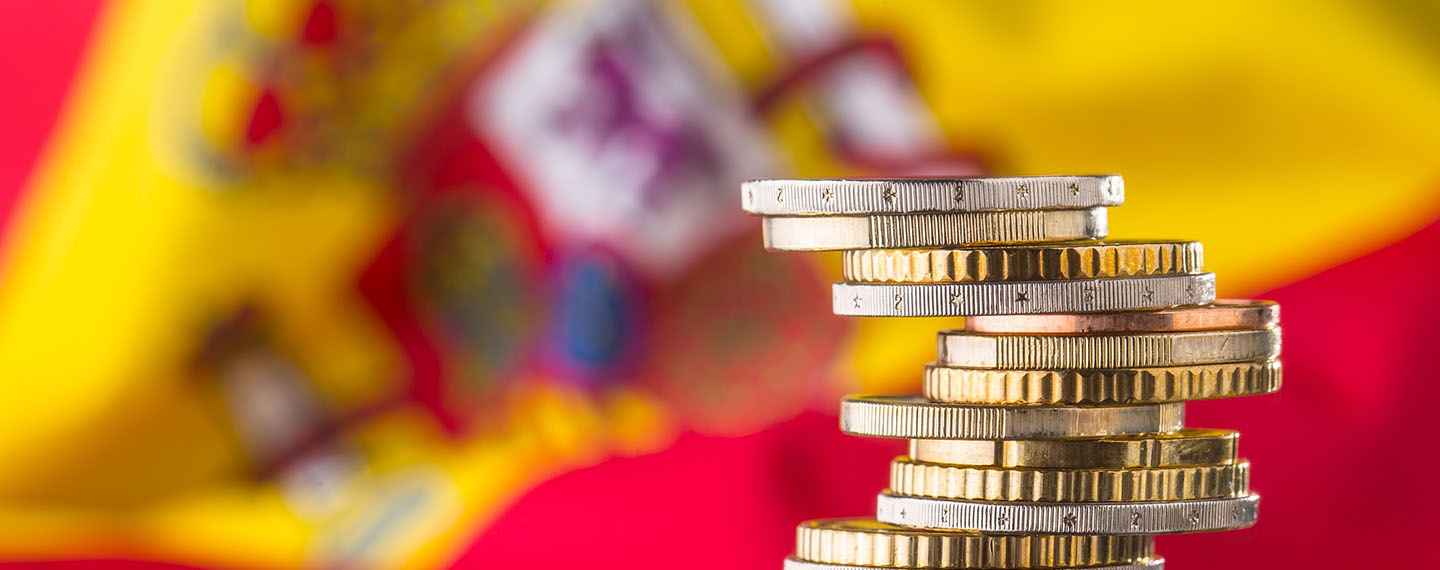 Close-up of stacked euro coins and in the background a blurred Spanish flag. Concept of the Spanish economy