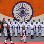 El primer ministro de la India, Narendra Modi, pasa revista a la Guardia de Honor durante el 77º acto del Día de la Independencia en el histórico Fuerte Rojo, el 15 de agosto de 2023 en Nueva Delhi. Modi es seguido por una guarda y al fondo un detalle de la bandera de India hecha con flores