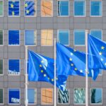 Three European Union (EU) flags fly in the wind at full mast outside the windows of the Berlaymont building, the headquarters of the European Commission (the EU executive) in Brussels, Belgium