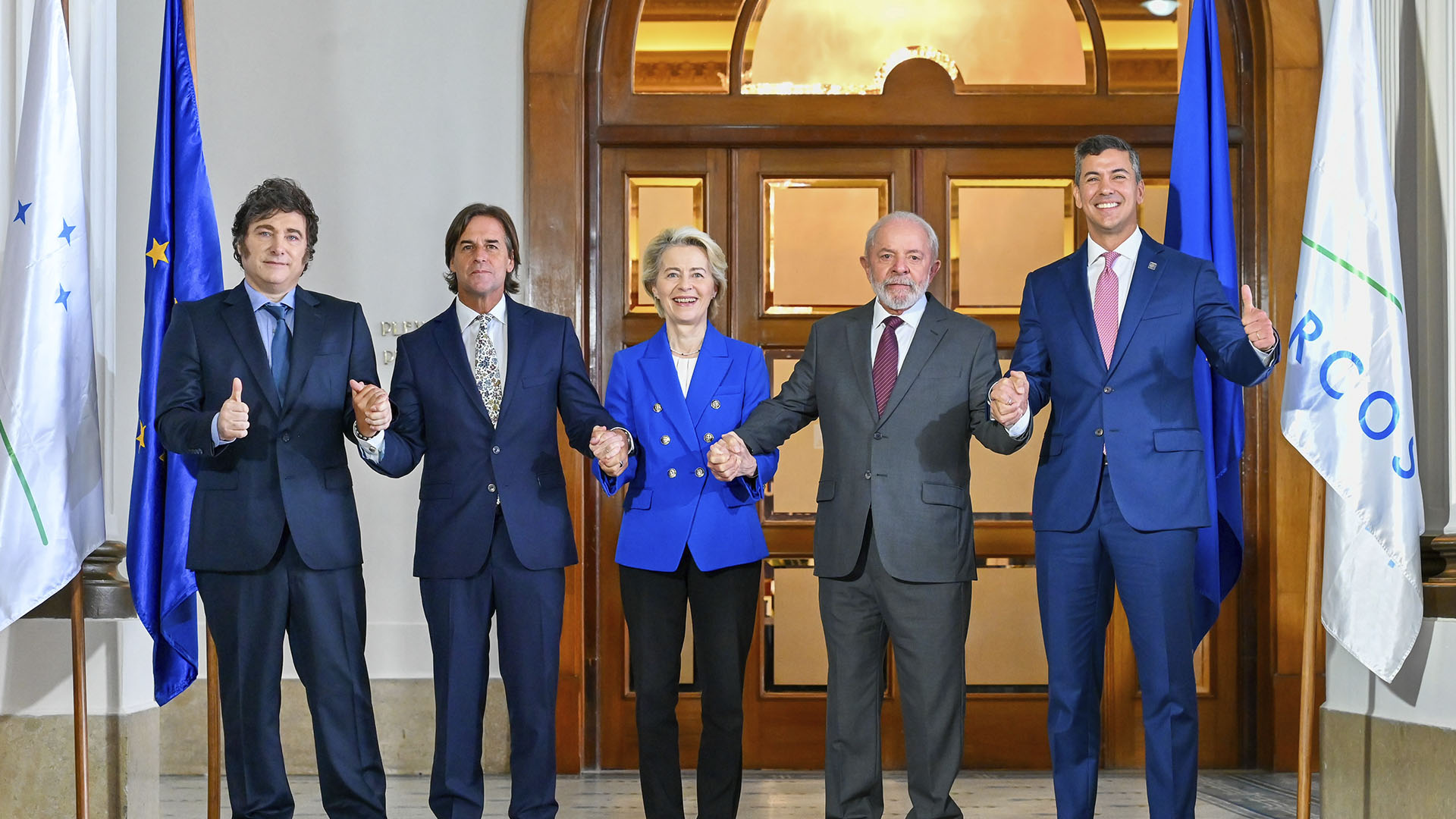 De izquierda a derecha: Javier Milei, Luis Alberto Lacalle Pou, Ursula von der Leyen, Luiz Inácio Lula da Silva, and Santiago Peña en Montevideo (Uruguay), tras alcanzar un acuerdo en las negociaciones para el Acuerdo UE-Mercosur en 2024. Al fondo, se aprecian las banderas de la Unión Europea y Mercosur. Acuerdo UE-Mercosur