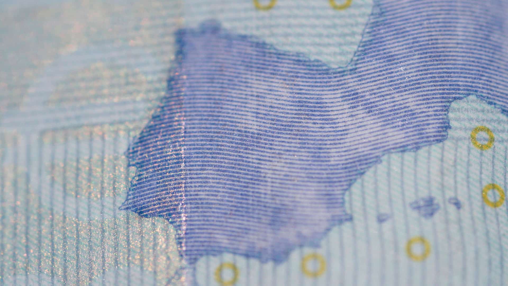 Detalle de un billete de 20 euros de una parte del mapa de Europa (la península Ibérica y parte de Francia), donde ser aprecia la textura del papel, el brillo parcial de la tinta, las líneas azules finas y pequeños círculos dorados