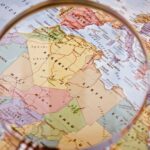 Expanded map of North Africa with a magnifying glass, detailing the countries along the Mediterranean coast (Morocco, Algeria, and Libya) and the Iberian Peninsula on the European continent. Gas