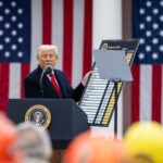 Donald Trump anuncia los aranceles “recíprocos” junto a Howard Lutnick, secretario de Comercio de EEUU (a la derecha), desde un atril con micrófono ante una audiencia congregada en el evento Make America Wealthy Again o “Día de la Liberación” en la Rosaleda de la Casa Blanca, el pasado 2 de abril de 2025. En su mano izquierda, Trump sostiene en alto una tabla con el listado de países y los aranceles (shock arancelario).