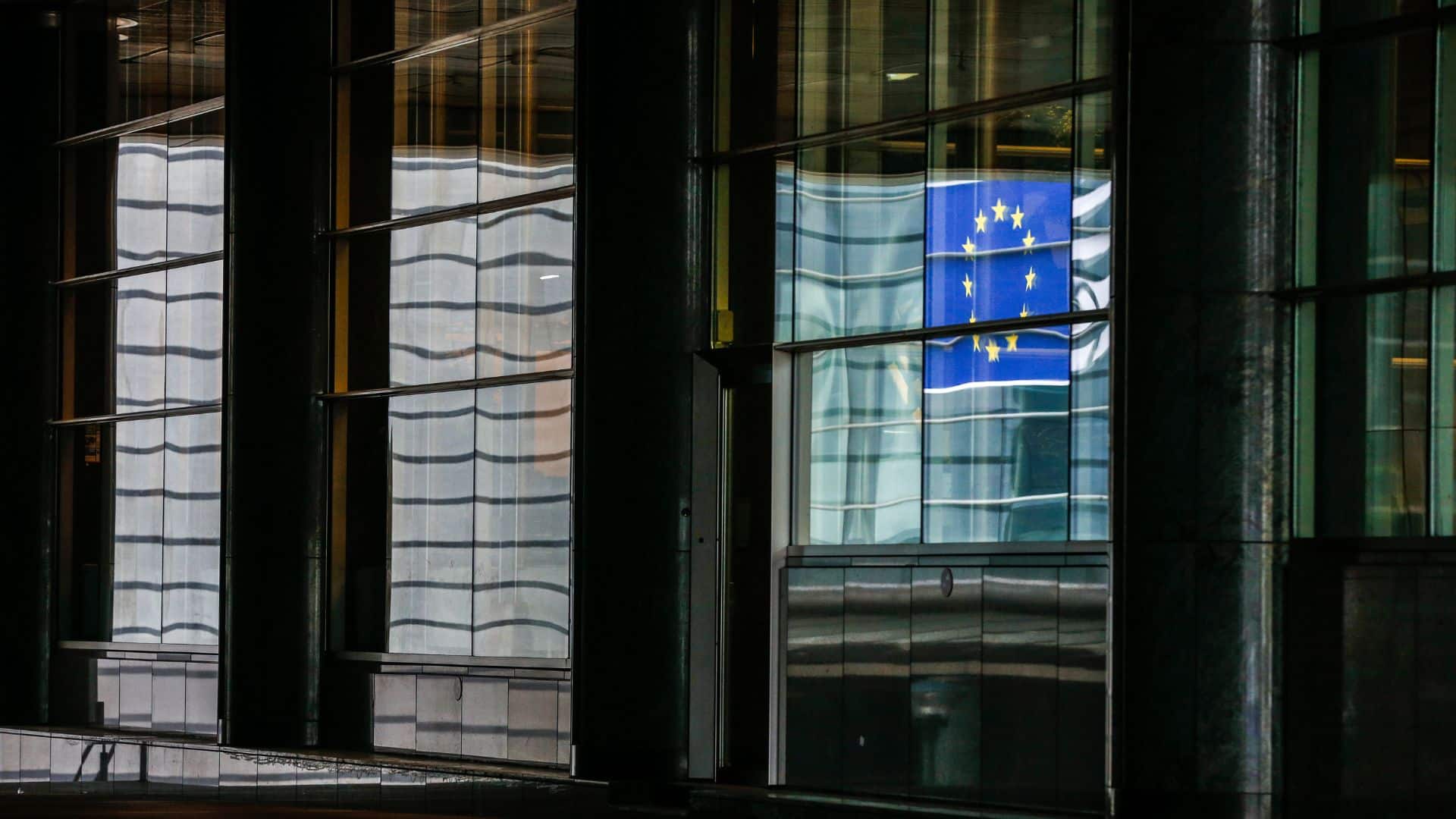 Detalle de la fachada acristalada del edificio del Parlamento Europeo en Bruselas (Bélgica), sobre la que se refleja la bandera azul con estrellas amarillas de la Unión Europea. Europa