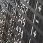 Un panel digital oscuro en la Bolsa de Frankfurt muestra datos del índice bursátil alemán DAX, con números grandes y brillantes que indican precios de acciones. Trump