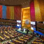 Panoramic view of the plenary of the UN General Assembly in New York, with tall vertical panels in bright colours representing the Sustainable Development Goals (SDGs). António Guterres gives a speech during the SDG conference on 18 September 2023. Photo: Michael Kappeler / picture Alliance / Getty Images.