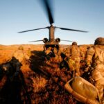 Spanish Army soldiers running towards a helicopter with its rotor blades spinning, during a field training exercise. Defence