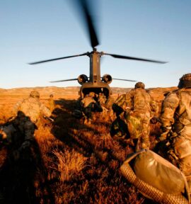 Soldados del Ejército de Tierra español corren hacia un helicóptero con las hélices en movimiento, durante un ejercicio militar en el campo. Defensa