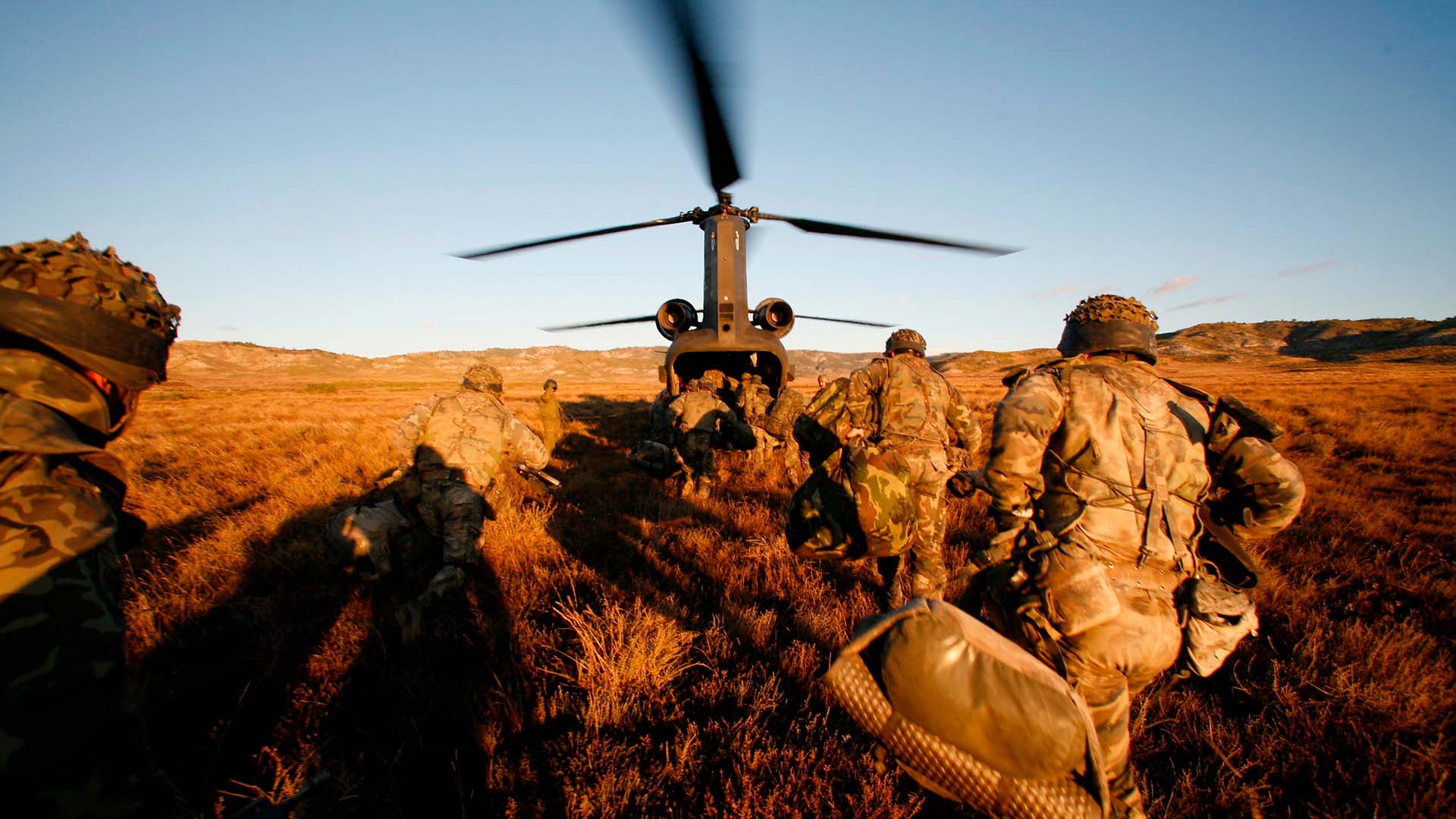Soldados del Ejército de Tierra español corren hacia un helicóptero con las hélices en movimiento, durante un ejercicio militar en el campo. Defensa