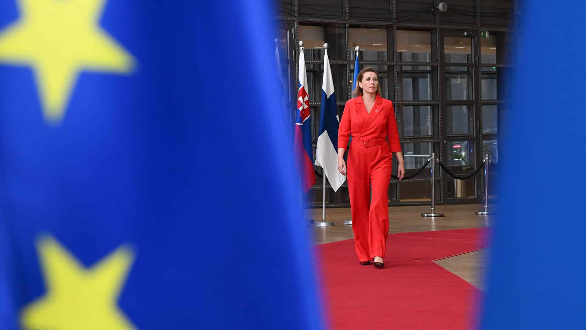 La primera ministra de Dinamarca, Mette Frederiksen, camina sobre la alfombra roja durante la cumbre del Consejo Europeo el 17 de octubre de 2024 en Bruselas, enmarcada por banderas de la UE. UE